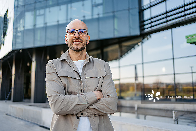 穿着休闲装站在公司大楼前的年轻商人图片素材