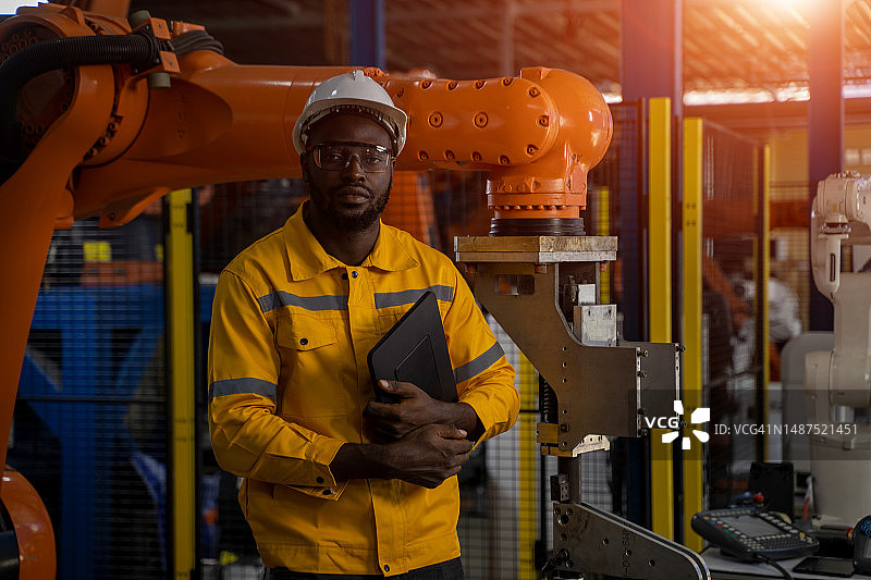机器人工程师在金属工业工厂检查并维护机器人，共同探讨正确方法图片素材