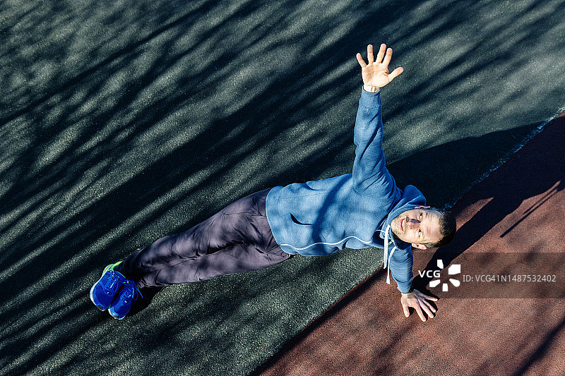 平板支撑姿势——男人在公园运动场的肌肉上锻炼核心图片素材