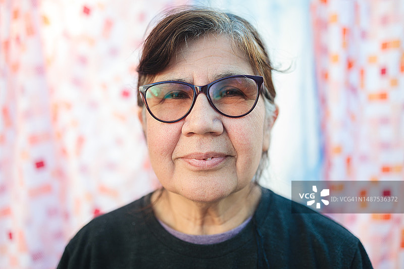 拉丁美洲妇女在自家后院的特写 портрет，背景挂着床单图片素材