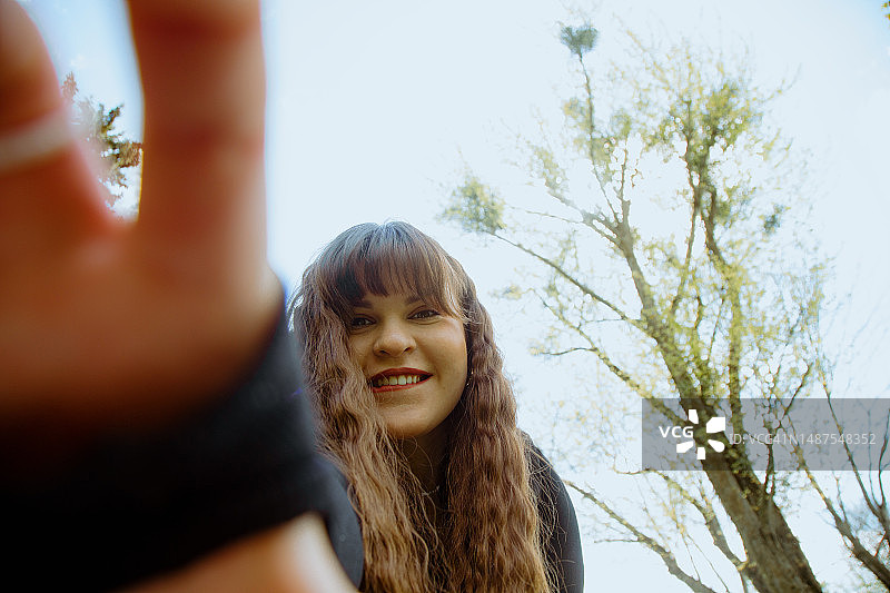 对着镜头微笑，伸出手的年轻女子图片素材