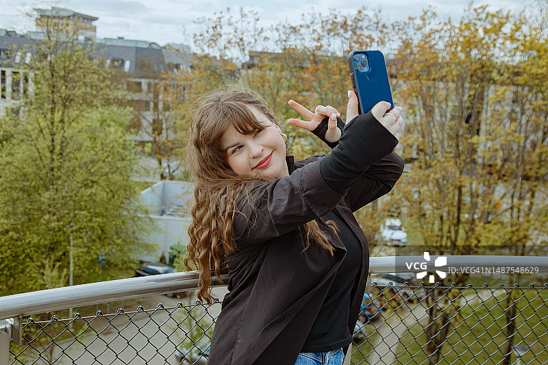 年轻漂亮的卷发女人在观景点自拍图片素材
