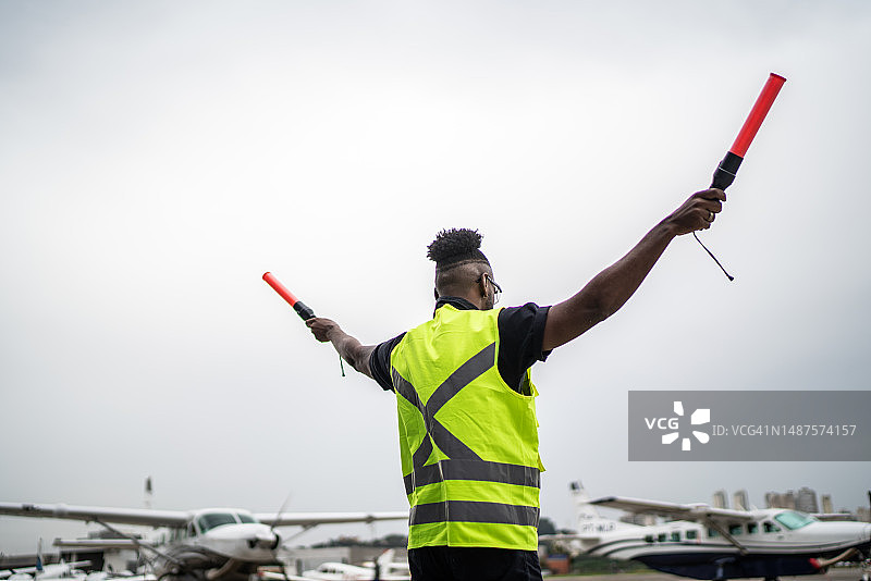 男子在机场用引导棒向飞行员发出信号图片素材