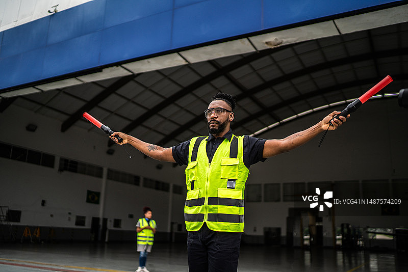 男子在机场用引导棒向飞行员发出信号图片素材