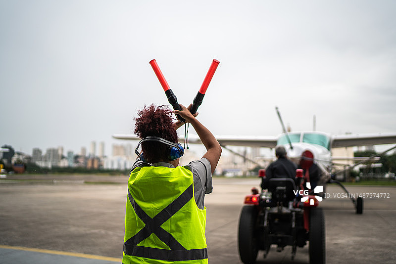 女人在机场用引导棒向飞行员发出信号图片素材