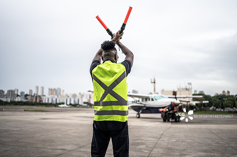 男子在机场用引导棒向飞行员发出信号图片素材