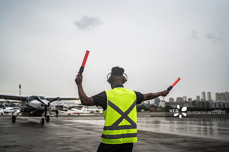 男子在机场用引导棒向飞行员发出信号图片素材