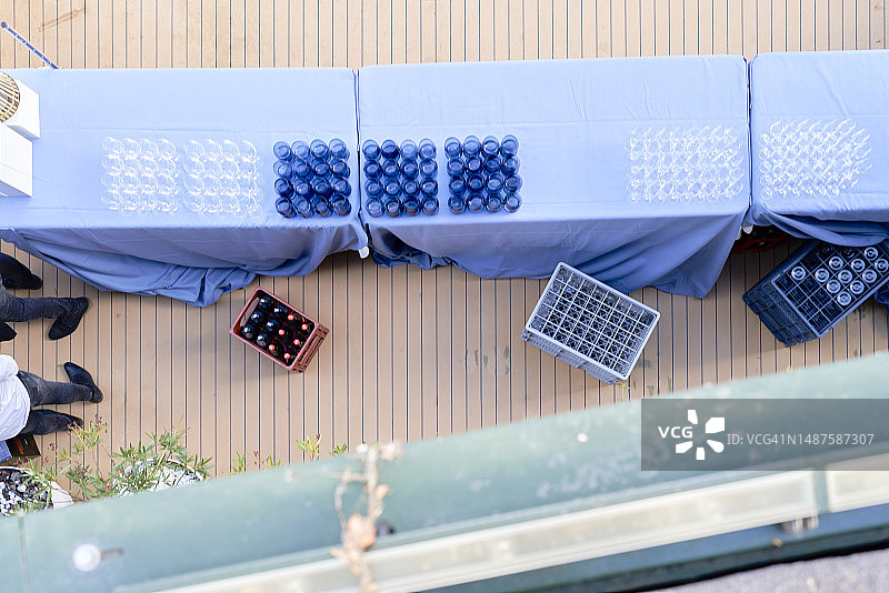 活动餐桌，饰有蓝色桌布、蓝色玻璃杯，以及苏打容器和两位人物图片素材