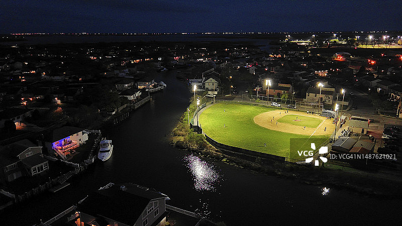夜间棒球比赛：业余球队在纽约海边社区体育场进行棒球比赛（航拍视角）图片素材