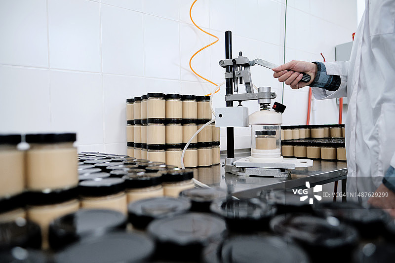 工厂工人用吸尘器清洁玻璃罐中的成品图片素材