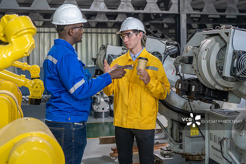 男人工程师在工厂检查机器人手臂焊接机图片素材