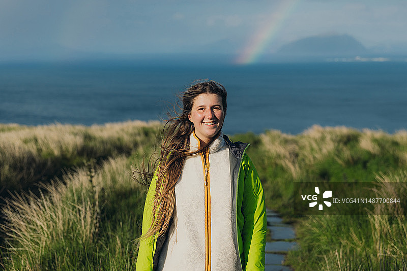 快乐的女人在挪威的伦德岛上在风景如画的海上彩虹下徒步旅行图片素材