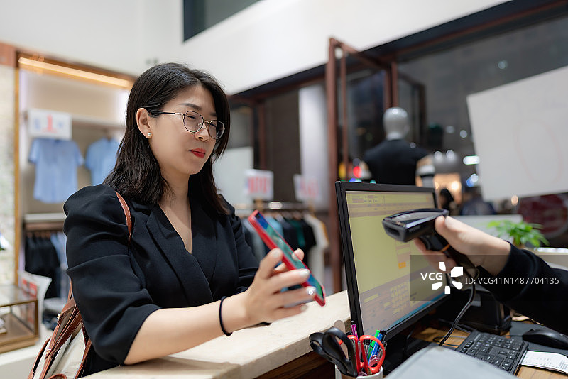 女士使用智能手机扫描二维码支付图片素材