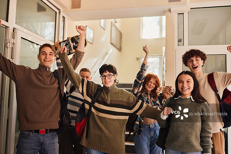 快乐的学生在走廊庆祝学年结束图片素材