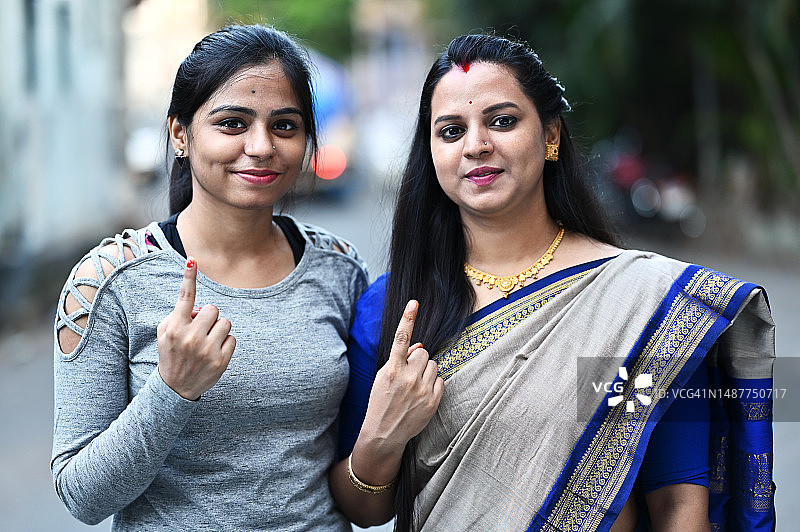 年轻女性在投票站外展示带有墨水标记的手指图片素材
