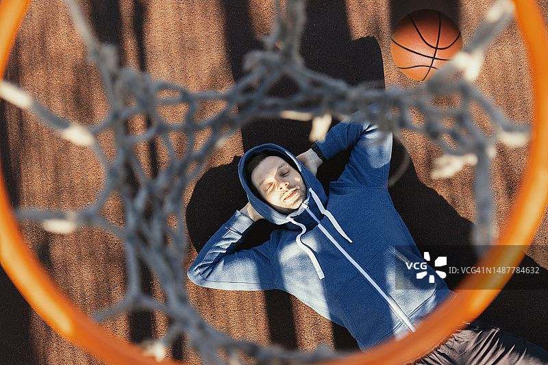 男子在篮球架下休息图片素材