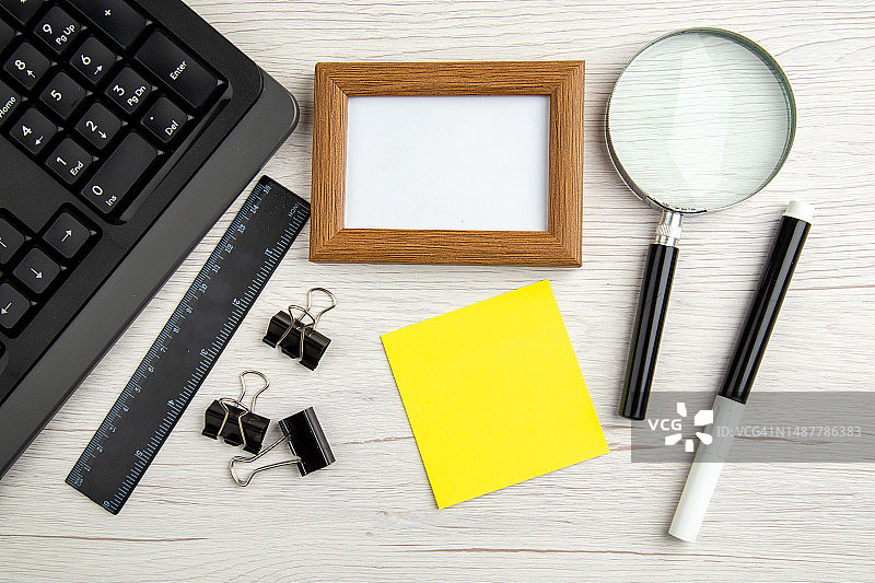 白色条纹背景上的棕色空画框和笔记本电脑等物品俯视图图片素材