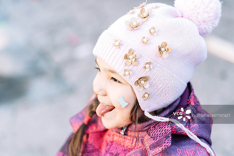戴帽子和穿暖和衣服的吐舌头的小女孩图片素材