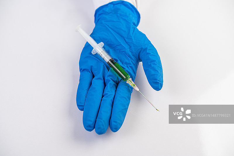 戴着口罩和手套的科学家拿着注射器研究疫苗，预防新冠病毒图片素材
