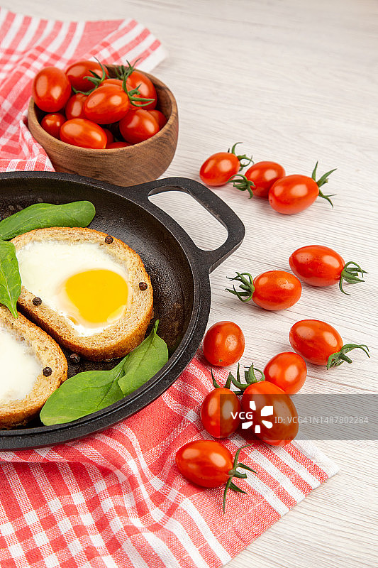 平底锅中鸡蛋吐司与红番茄，白色背景图片素材