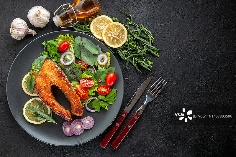 俯视角度拍摄的美味烹饪鱼，配以新鲜蔬菜和调味料图片素材