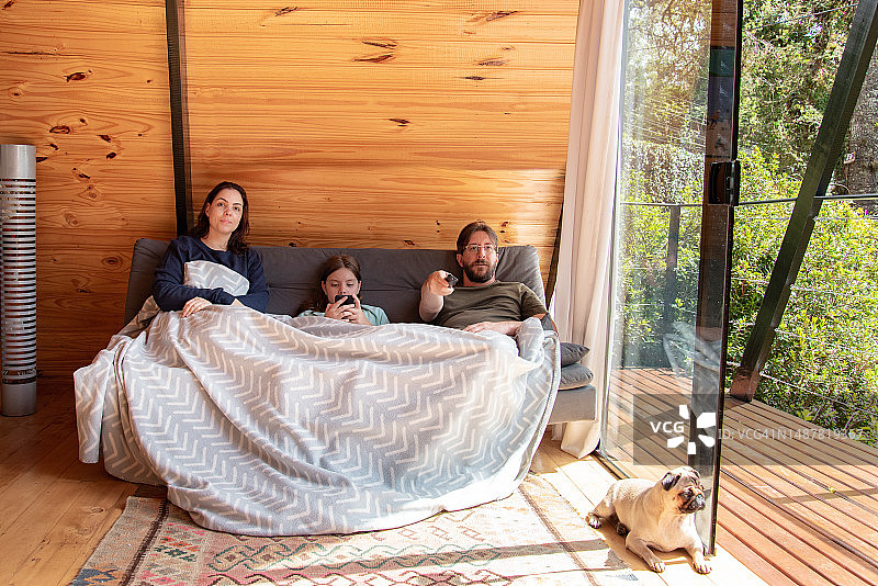 一家人盖着毯子在沙发上看电视图片素材