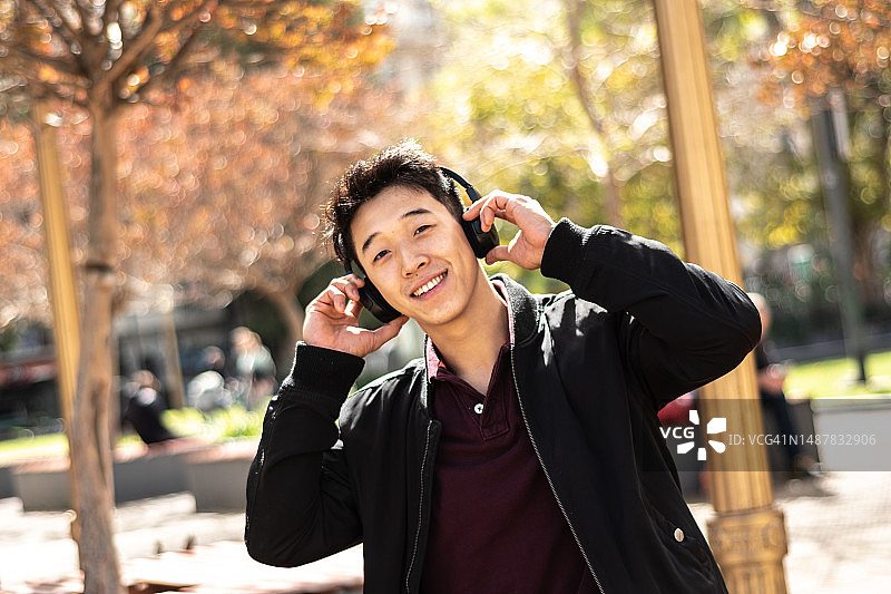 年轻男人戴无线耳机在户外听音乐的肖像图片素材