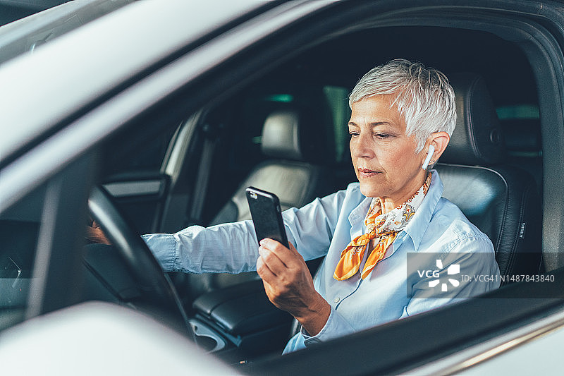 年长的女人在车里使用智能手机图片素材