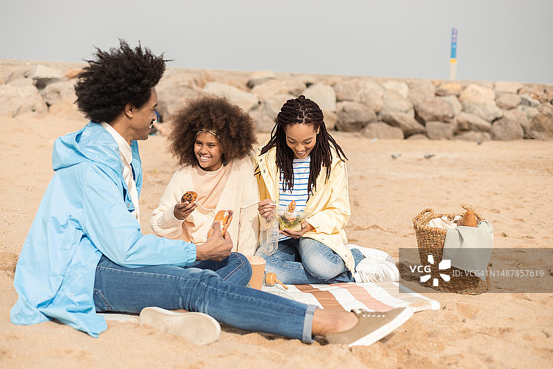 非洲裔少女与父母在海滩野餐图片素材