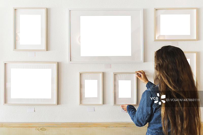 女人将相框挂在墙上图片素材