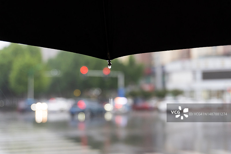 雨伞上的雨滴与雨中城市街景虚化特写图片素材
