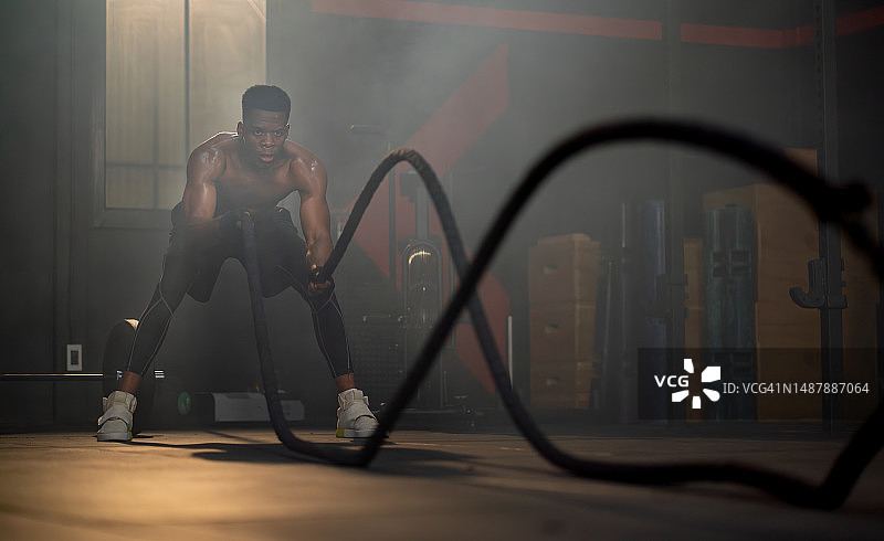 非裔美国运动员在健身房通过甩绳或猛拉绳索来锻炼，以获得健康的身体图片素材