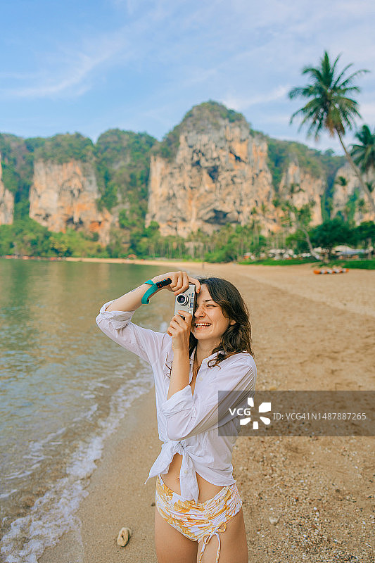 在海滩上用傻瓜相机拍照的女人图片素材