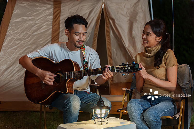 亚洲夫妇在户外露营时弹吉他唱歌图片素材