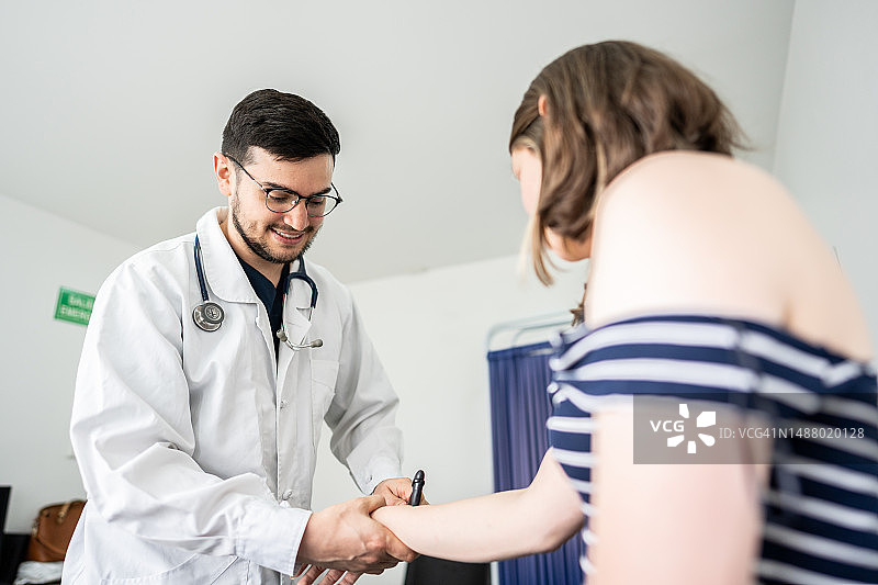 医生/理疗师在医疗诊所使用反射锤检查病人的手臂图片素材