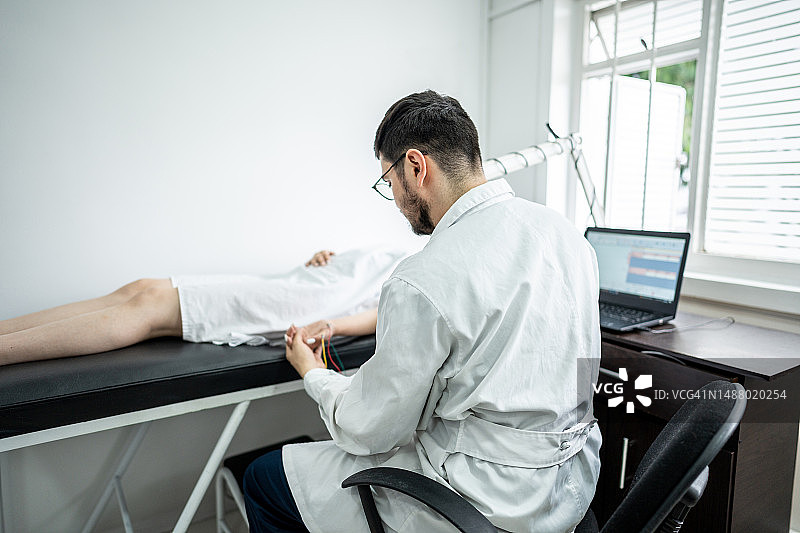 医生在医疗诊所使用运动神经传导设备为患者检查图片素材