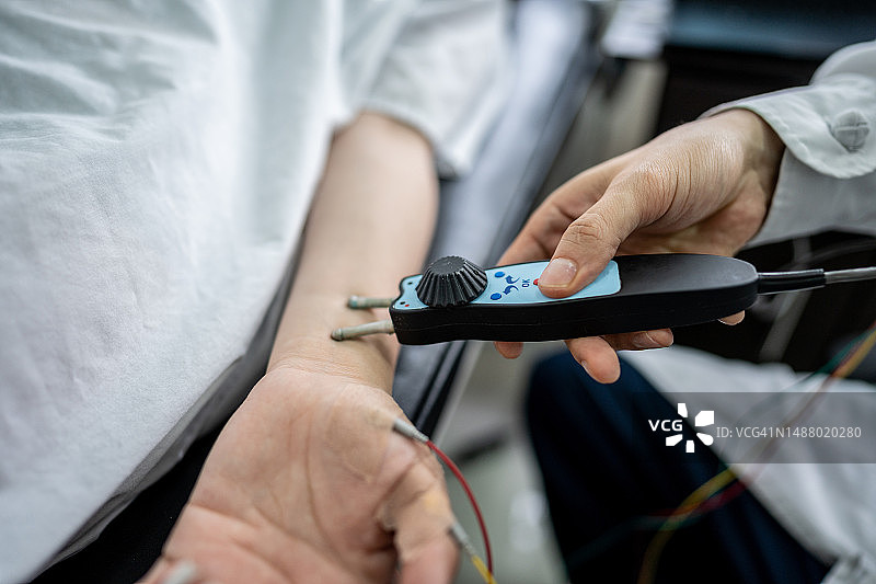 医疗诊所医生使用运动神经传导设备为病人检查特写图片素材