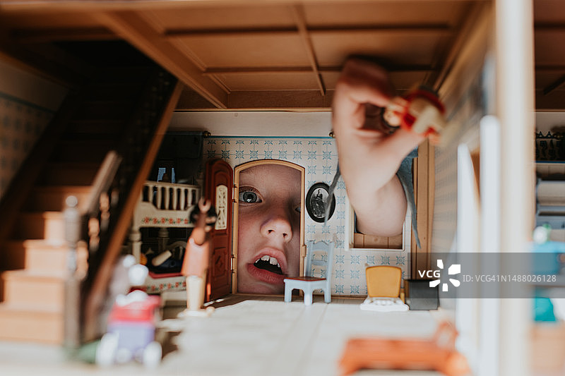小女孩从娃娃屋的门往里看图片素材