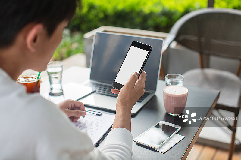 手持黑色手机喝咖啡图片素材