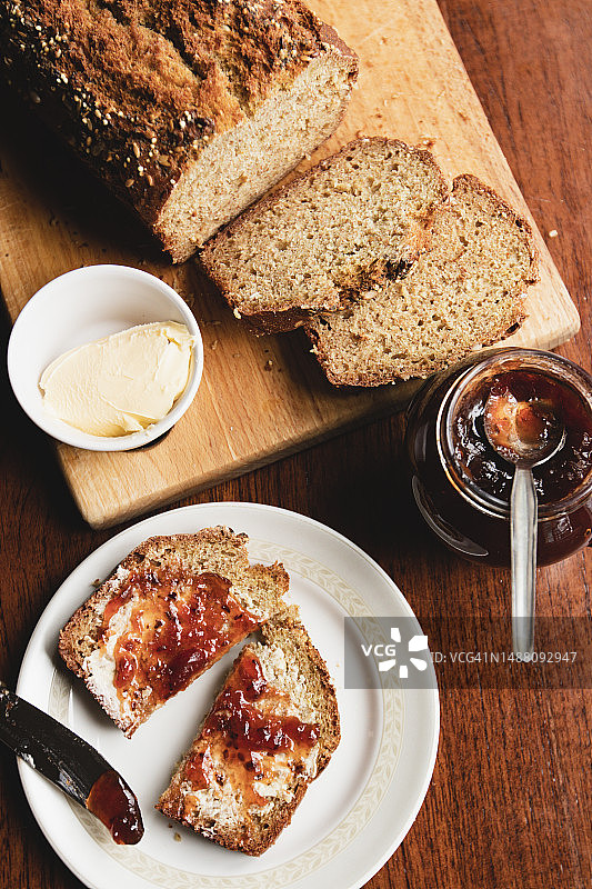 俯视：切片黑面包、果酱和黄油，小盘中已涂抹黄油和果酱图片素材