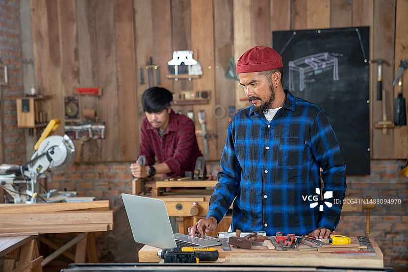亚洲木工团队使用电脑设计，在家进行木工图片素材