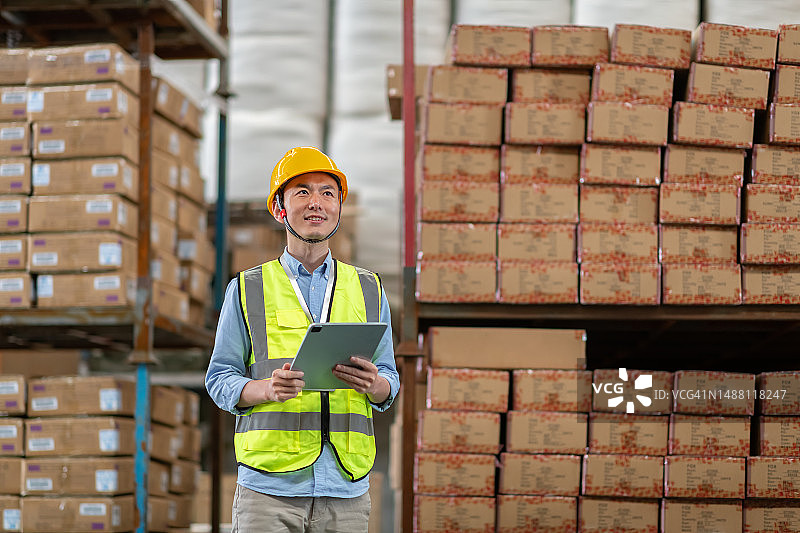 亚洲男性仓库管理员使用平板电脑管理货物图片素材