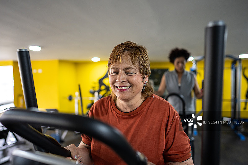 在健身房的椭圆机上锻炼的中年妇女图片素材