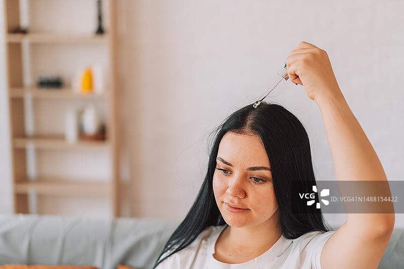 女士用滴管在头皮上涂抹精华液图片素材