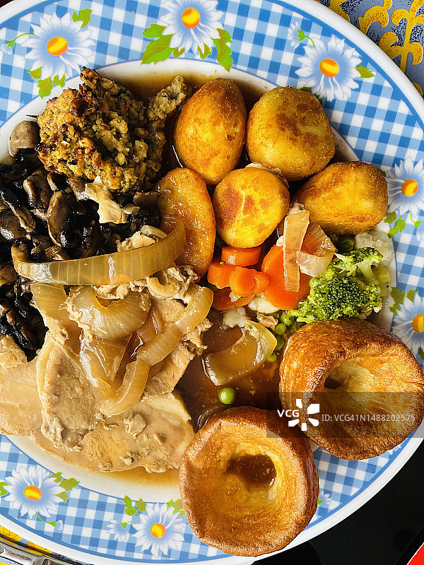 英式食品拼盘，包括烤猪肉、烤土豆、馅料、蘑菇、混合蔬菜、约克郡布丁和洋葱肉汁特写图片素材