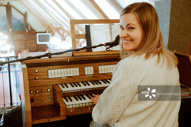 女人坐在风琴前，转过身对着镜头微笑图片素材