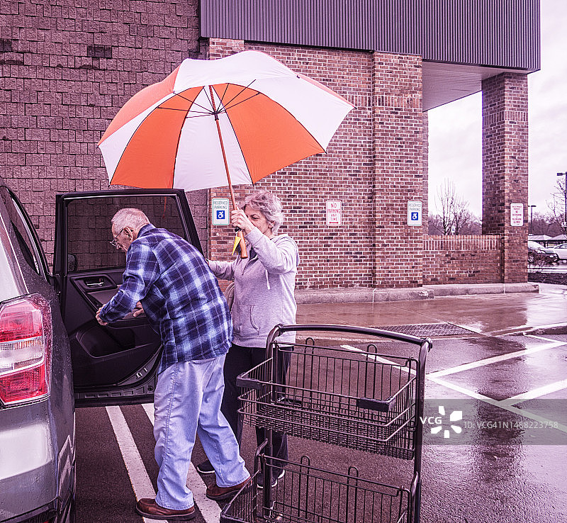 居家护理员女儿在超市为年迈的父亲撑伞图片素材