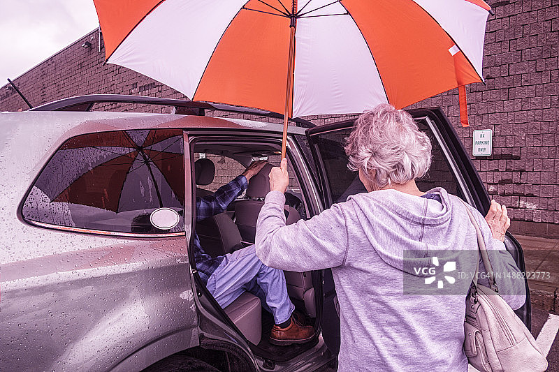 成年女儿撑伞照顾年迈的父亲图片素材