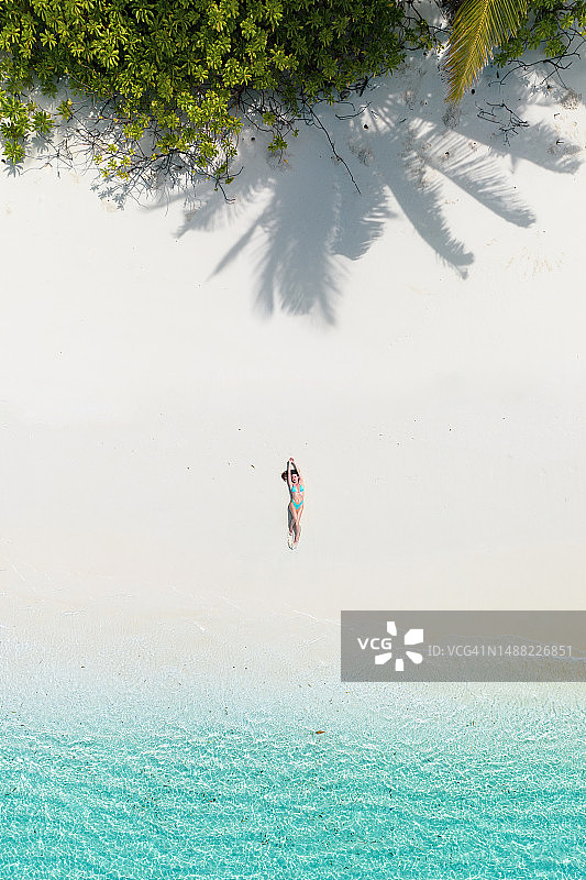 一名女子躺在沙滩上的无人机航拍图片素材