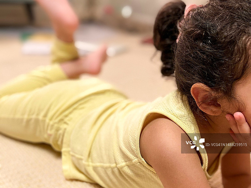 年轻的混血女孩在地板上放松，手托着下巴图片素材